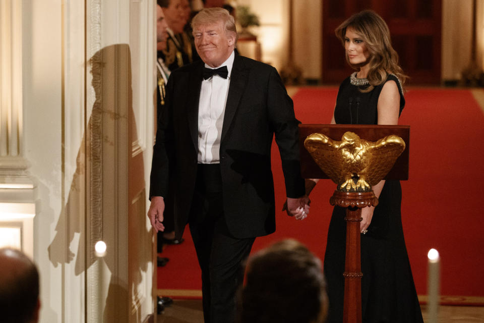 President Donald Trump holds hands with first lady Melania Trump as they take their seats after he spoke at the Governors' Ball, Sunday, Feb. 9, 2020, in the East Room of the White House in Washington. (AP Photo/Jacquelyn Martin)