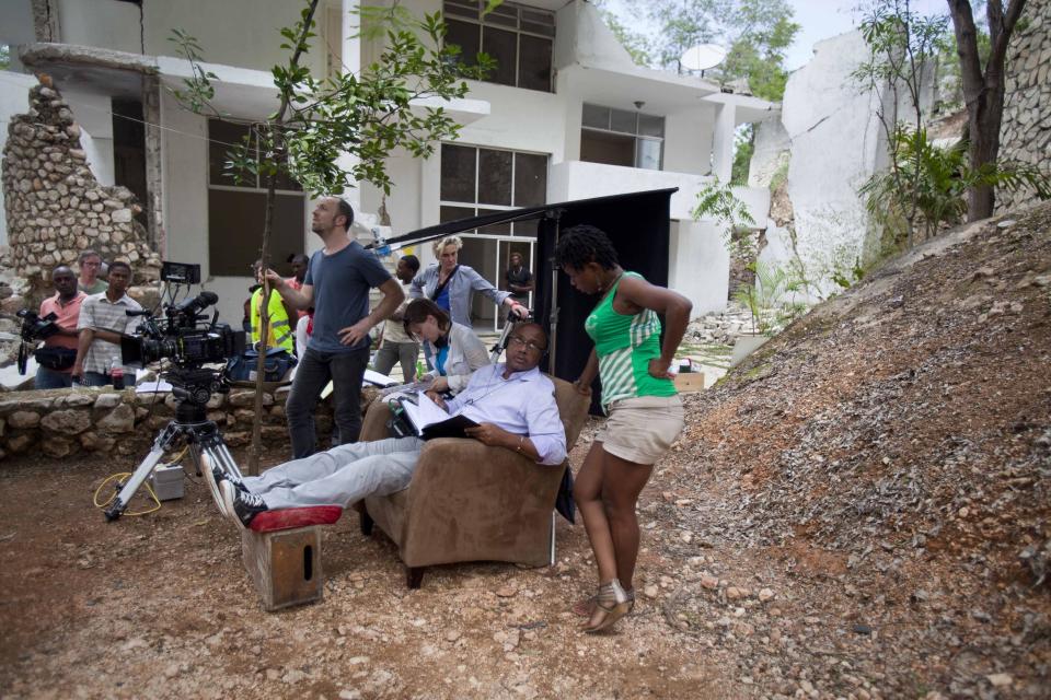 Haitian film Director Raoul Peck, sitting center, speaks with Haitian actress Lovely Kermonde Fifi on the set of the film "Murder in Pacot" at a home that was damaged in the 2010 earthquake in Port-au-Prince, Haiti, Friday, April 11, 2014. Peck, whose past films include "The Man by the Shore" about dictatorship-era Haiti, the Rwanda genocide drama "Sometimes in April" and "Lumumba: Death of a Prophet," said he came up with the idea for the film while shooting "Fatal Assistance," a documentary that takes a harsh look at Haiti's reconstruction effort. (AP Photo/Dieu Nalio Chery)