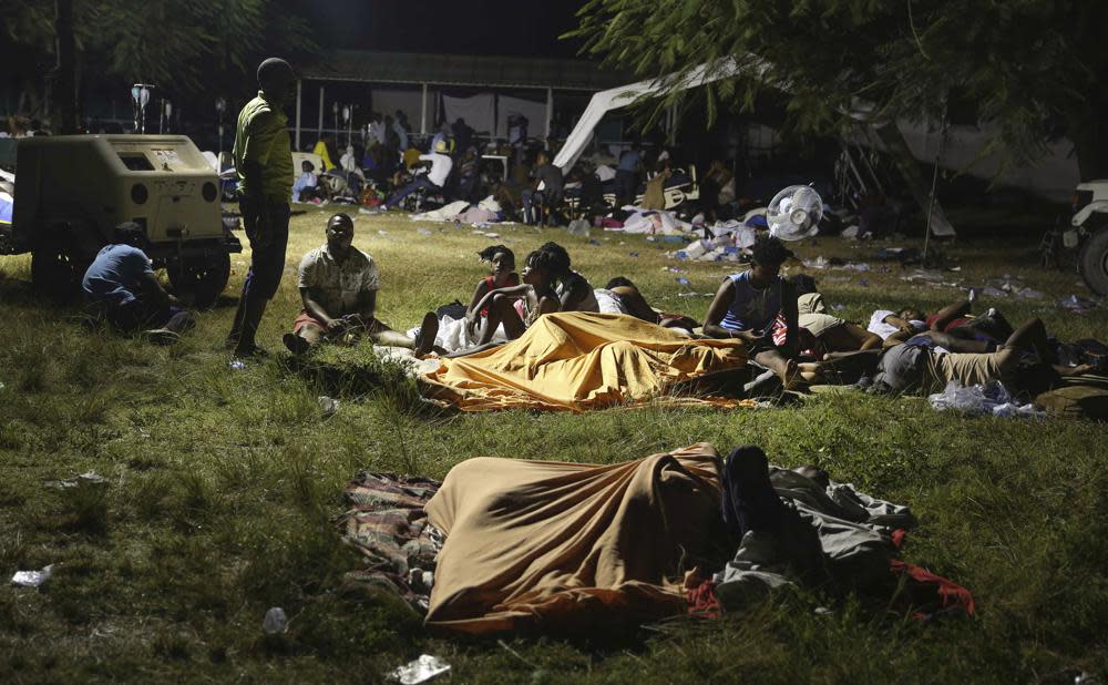 People displaced from their earthquake destroyed homes spend the night outdoors in a grassy area that is part of a hospital in Les Cayes, Haiti, late Saturday, Aug. 14, 2021. (AP Photo/Joseph Odelyn)