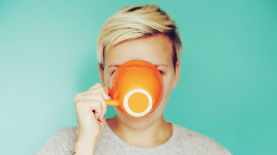 young woman drinking out of an orange cup