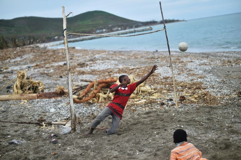 Children play fooball on a damaged beach on October 19, 2016 in the aftermath of Hurricane Matthew in the commune of Port-a-Piment, southwestern Haiti