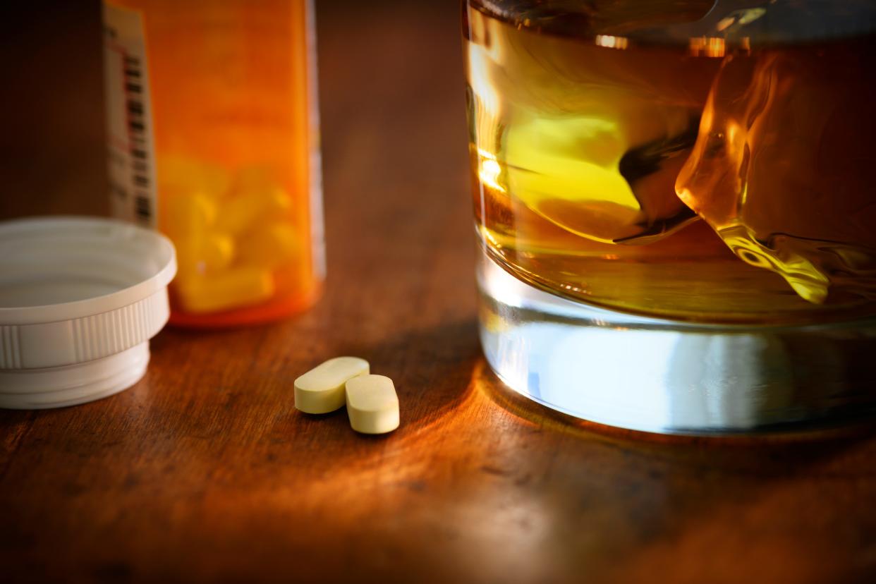 A photo showing a glass of whiskey next to oxycodone.