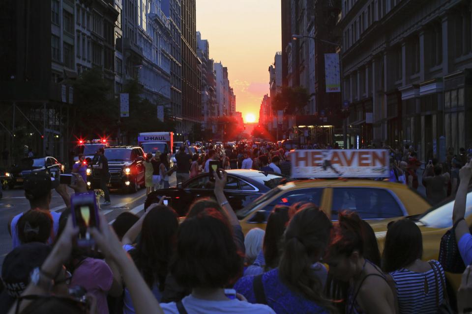 People take pictures at sunset during the bi-annual occurrence "Manhattanhenge" in New York