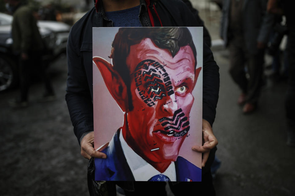 FILE - In this Oct.30, 2020 file photo, a man holds a poster with a caricature of France's President Emmanuel Macron, depicting him as devil during a protest against France in Istanbul. A spotlight of suspicion encircled Muslims again even before the latest acts of extremist violence, including two beheadings. French President Emmanuel Macron has forged ahead with a plan to rid Islam in France of extremists, part a project he labels "separatism," a term that makes some Muslims wince. (AP Photo/Emrah Gurel, File)