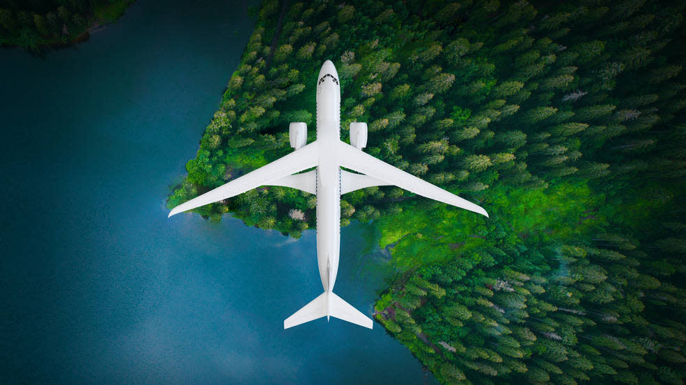  graphic illustration showing an aerial view of the X-66A plane flying above water and a forested area to the right. 