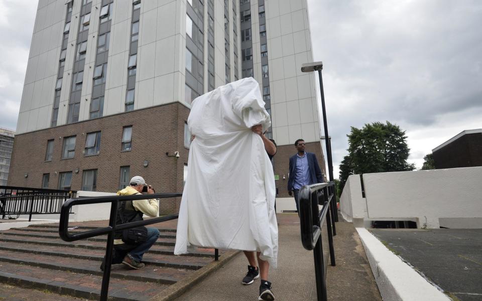 A man carries a mattress from the Dorney Tower residential block - Credit: Hannah McKay /Reuters