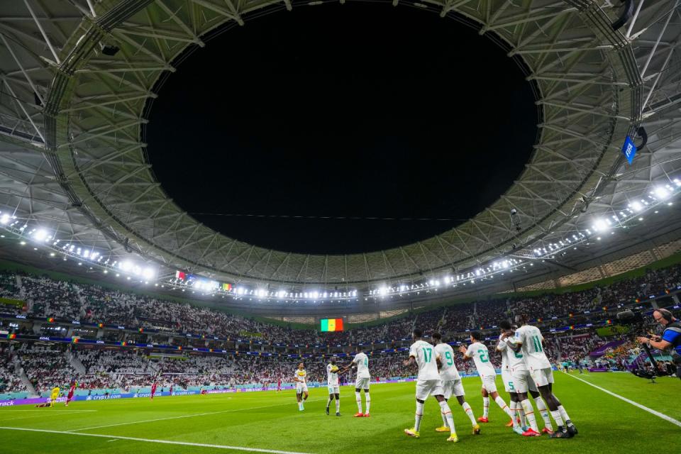 Temmates celebrate with Senegal's Bamba Dieng after he score their third goal against Qatar during a World Cup group A football match at the Al Thumama Stadium in Doha, Qatar, Friday, Nov. 25, 2022. (AP Photo/Petr Josek)