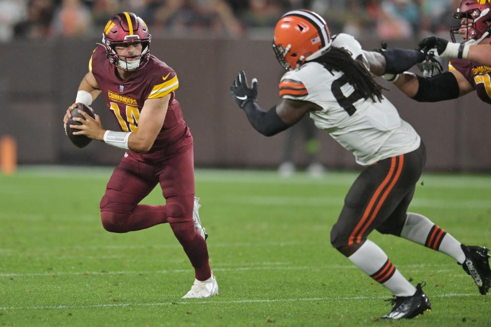 Washington Commanders quarterback Sam Howell (14) scrambles from Cleveland Browns defensive end Lonnie Phelps (63) during the first half at Cleveland Browns Stadium.