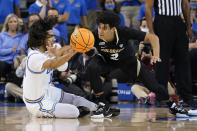 UCLA guard Tyger Campbell, left, passes the ball from the floor while defended by Colorado guard KJ Simpson (2) during the first half of an NCAA college basketball game in Los Angeles, Wednesday, Dec. 1, 2021. (AP Photo/Ashley Landis)