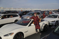 Graduate Trevor Barrett sits on a car during a drive-thru graduation for Faith Lutheran High School at the Las Vegas Motor Speedway, Friday, May 22, 2020, in Las Vegas. The school held a special drive-thru graduation amid the coronavirus pandemic. (AP Photo/John Locher)