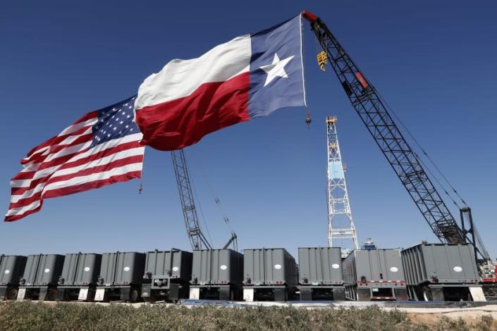 An American and Texas flag fly from the tops of cranes near an oil rig by the site where President Donald Trump delivered remarks about American energy production during a visit to the Double Eagle Energy Oil Rig, Wednesday, July 29, 2020, in Midland, Texas. (AP Photo/Tony Gutierrez)