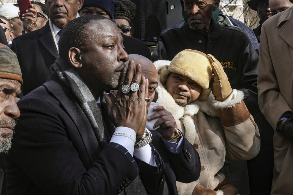 Yusef Salaam, with hands together, Raymond Santana Jr., center, and Kevin Richardson, right, wearing hat, three of five men exonerated after being wrongfully convicted as teenagers for the 1989 rape of a jogger in Central Park, listen during a ceremony to name the northeast gateway of Central Park as "The Gate of the Exonerated," Monday Dec. 19, 2022, in New York. The entrance was named to honor Salaam, Santana, Richardson, Antron McCray and Korey Wise, who were the five men exonerated in the case. (AP Photo/Bebeto Matthews)