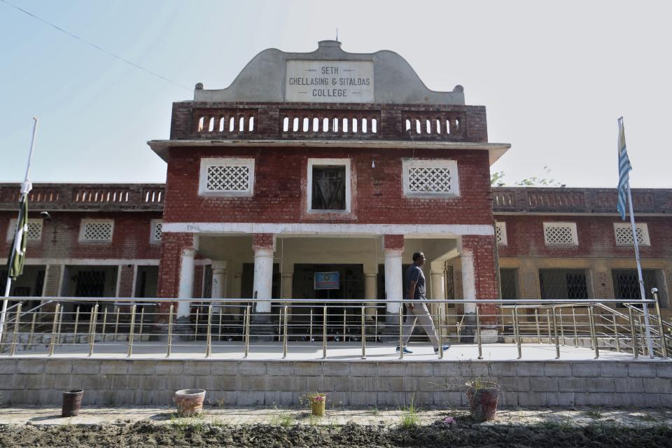 A man walks in a historical college named on Chella Singh and Sital Das, Hindu bankers who donated the bulk of funding for the construction of college, in Shikarpur, Pakistan, Wednesday, Oct. 26, 2022. The landscape of Pakistan, and Sindh in particular, retains their imprint. It has temples, although their numbers have plummeted, businesses, education and healthcare institutions, many established before the country was created in 1947. These places are part of Pakistan's heritage, even as Hindus are forced into the shadows. (AP Photo/Fareed Khan)