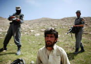 <p>Afghan policemen stand next to a captured Taliban fighter after a gun battle near the village of Shajoy in Zabol province March 22, 2008. (Photo: Goran Tomasevic/Reuters) </p>