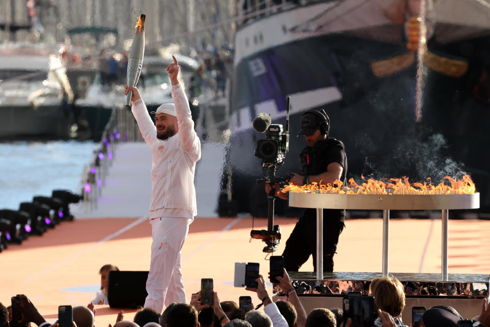 French rapper Julien Mari, aka Jul, holds the Olympic torch during the   arrival ceremony for the Olympic flame ahead of the   2024 Paris Olympic Games on May 8, 2024, in Marseille, France. / Credit: Arnold Jerocki/Getty Images