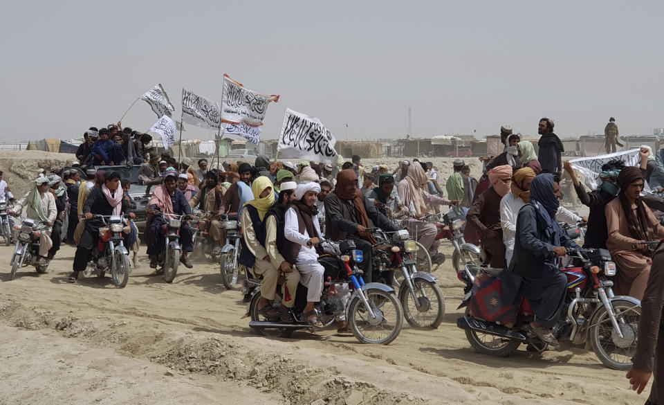 Supporters of the Taliban carry the Taliban's signature white flags in the Afghan-Pakistan border town of Chaman, Pakistan, Wednesday, July 14, 2021. The Taliban are pressing on with their surge in Afghanistan, saying Wednesday that they seized Spin Boldaka, a strategic border crossing with Pakistan — the latest in a series of key border post to come under their control in recent weeks. (AP Photo/Tariq Achkzai)