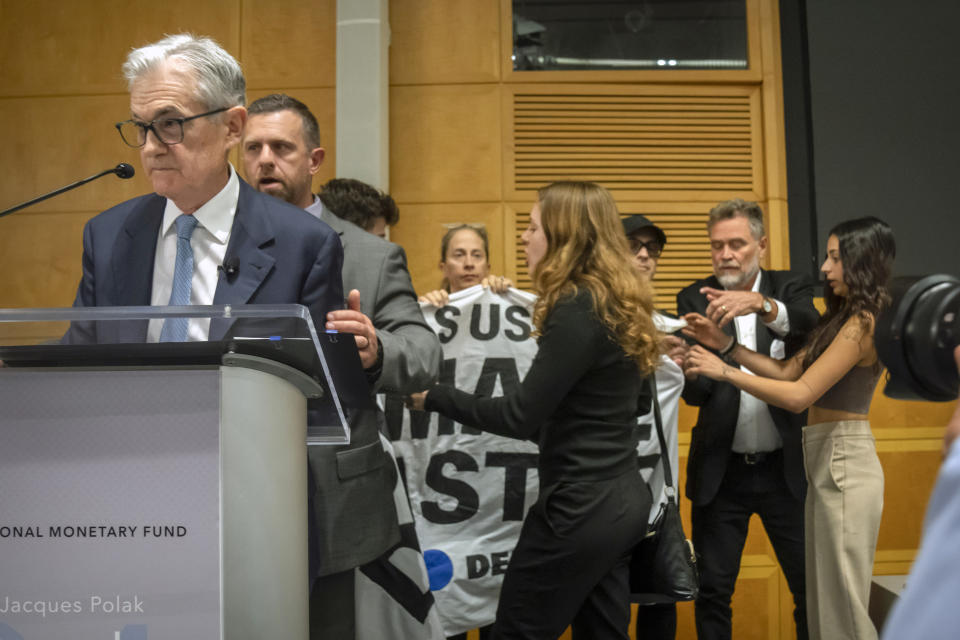Federal Reserve Chairman Jerome Powell is escorted off stage after climate protestors interrupted his speech at the 24th Jacques Polak Research Conference at the International Monetary Fund on Thursday, Nov. 9, 2023 in Washington. (AP Photo/Mark Schiefelbein)