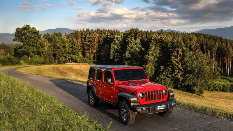 A photo of a red Jeep Wrangler on a country road. 