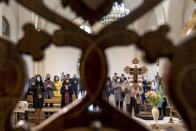 In this photo taken on Sunday, May 24, 2020, believers, some wearing face masks, attend a Mass conducting by Father Vasyl Gasynets, Ukrainian Greek Catholic Church priest, at a church in Chernivtsi, Ukraine. Gasynets has returned to conducting services at his Greek Catholic church in priestly raiment, but wearing a mask while distributing communion. (AP Photo/Evgeniy Maloletka)