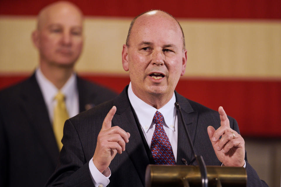 Neb. Gov. Pete Ricketts, rear, listens as Scott Frakes, director of the Nebraska Department of Correctional Services, speaks during a news conference in Lincoln, Neb., Friday, April 10, 2020, on developments in the struggle against the coronavirus. (AP Photo/Nati Harnik)