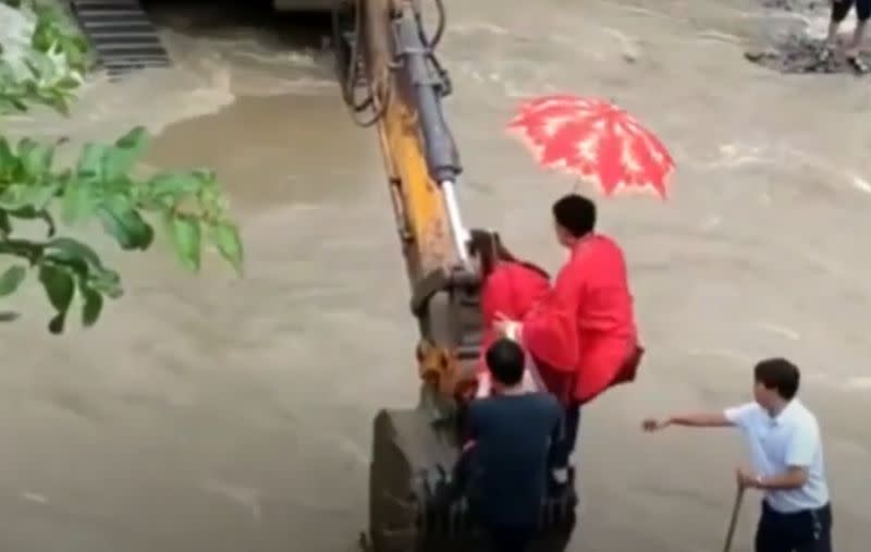 ▲湖北 1 對新婚夫妻，大喜之日卻遇到暴雨洪水，竟就坐在挖土機上渡河。（圖／擷取自影片）