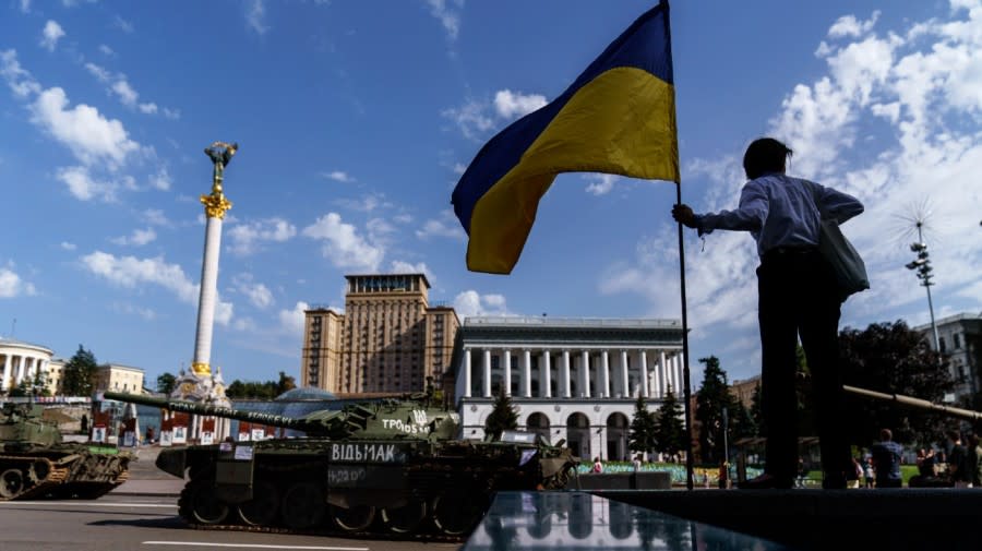 <span>A woman holds the flag of Ukraine while looking over a row of destroyed Russian military vehicles on display at Maidan Square in Kyiv, Ukraine, Tuesday, Aug. 23, 2022. (AP Photo/David Goldman)</span>