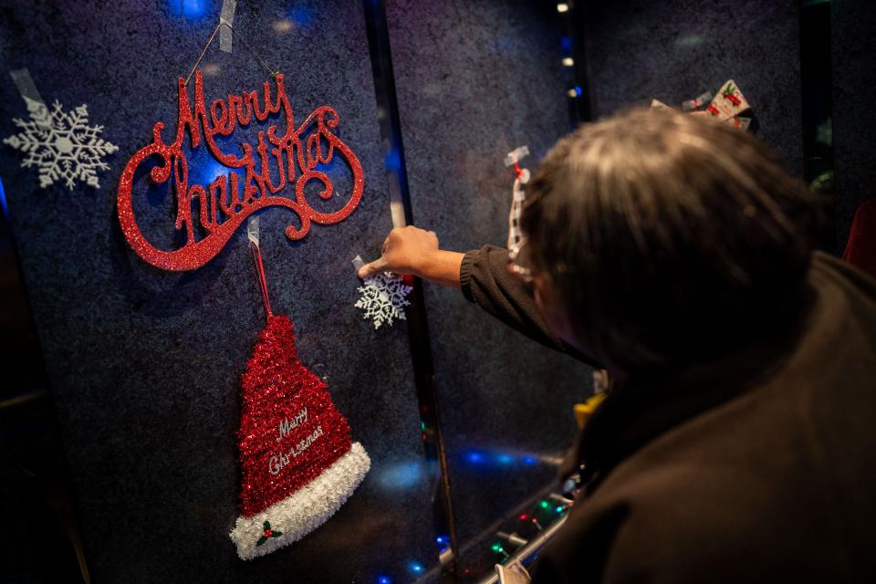 Elevator attendant Martha Booker decorates her elevator before a game between the Nashville Predators and the Dallas Stars at Bridgestone Arena in Nashville, Tenn., Saturday, Dec. 23, 2023.