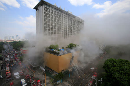Firefighters douse water after a fire engulfed the Manila Pavilon hotel in Metro Manila, Philippines March 18, 2018. REUTERS/Romeo Ranoco
