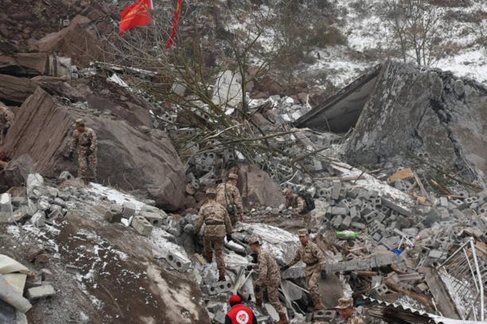 This picture taken on 22 January 2024 shows Chinese military police and rescue workers searching for missing victims at a landslide site in Liangshui village in Zhaotong, in southwestern China’s Yunnan province (AFP via Getty Images)