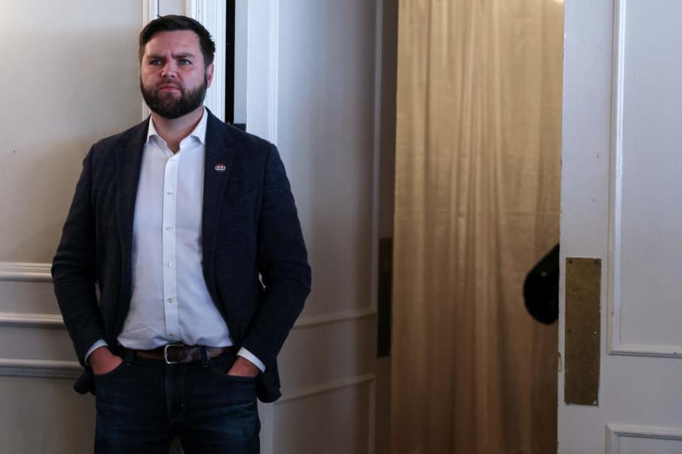 J.D. Vance stares forward blankly at a campaign event.