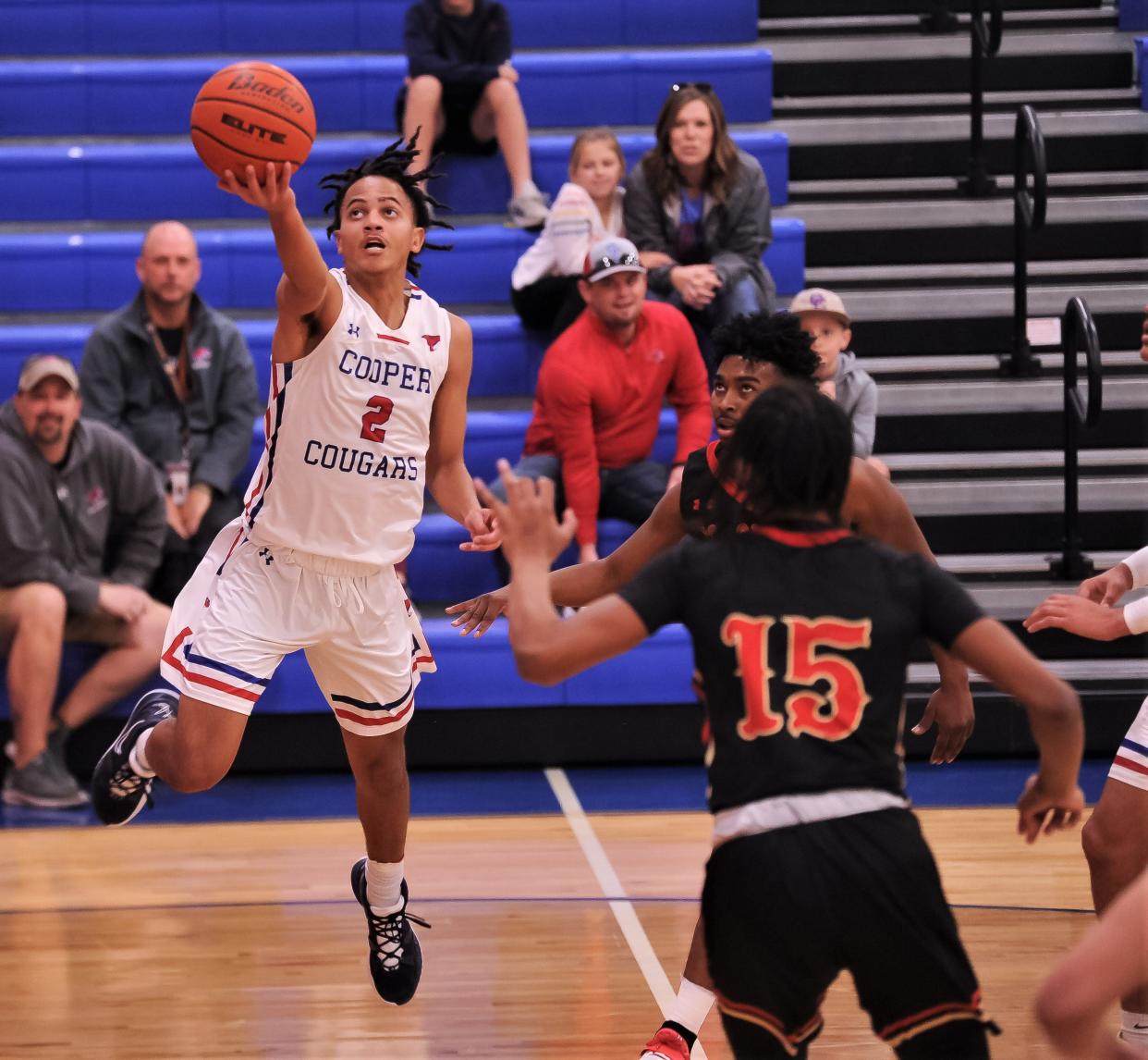 Cooper's Colin Reed (2) drives to the basket as Lubbock Coronado's Tyler Williams (15) and a teammate defend in the first half. Reed scored a game-high 35 points in the Coogs' 67-46 victory over the Mustangs on Saturday in a District 4-5A game at Cougar Gym.