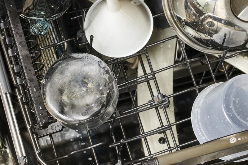 overhead shot of a used candle jar in the top rack of a dishwasher