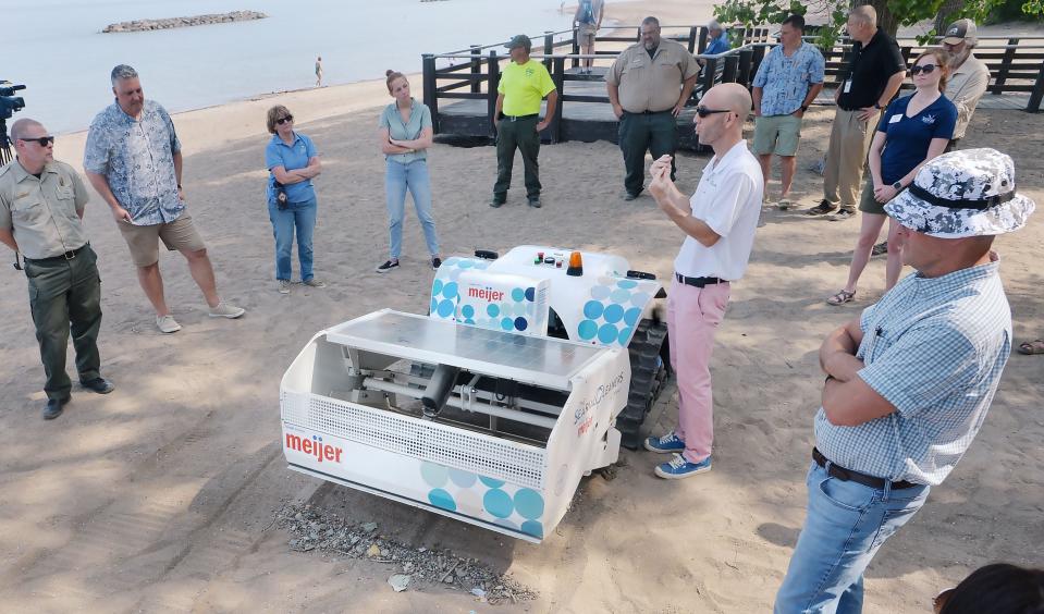 Gautier Peers, center, with The Searial Cleaners, holds small trash and plastic items cleaned Tuesday from an area of Presque Isle State Park's Beach 7. Peers demonstrated his company's robotic BeBot that cleans plastic and other trash from beaches, helping reduce the amount of plastics in waterways.