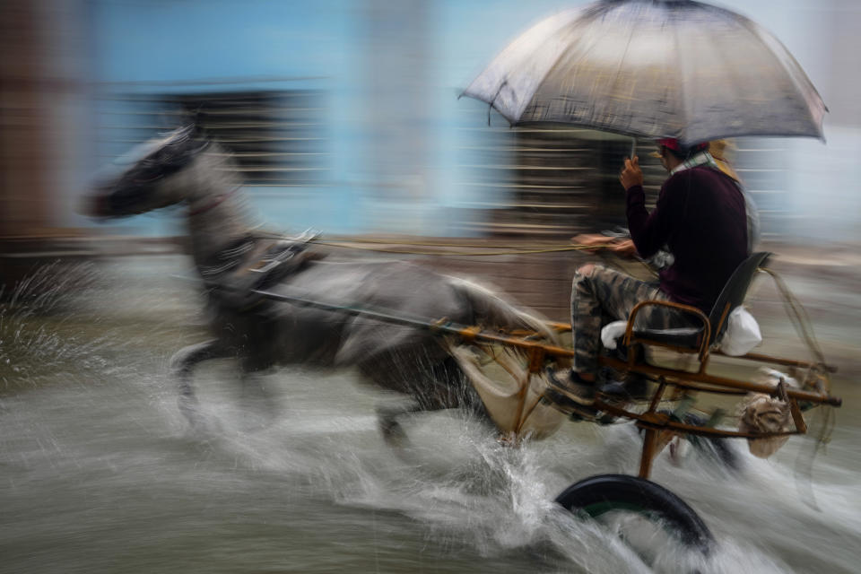 A horse pulls a buggy with passengers through a street flooded by heavy rains, in Havana, Cuba, on June 3, 2022. (AP Photo/Ramon Espinosa)