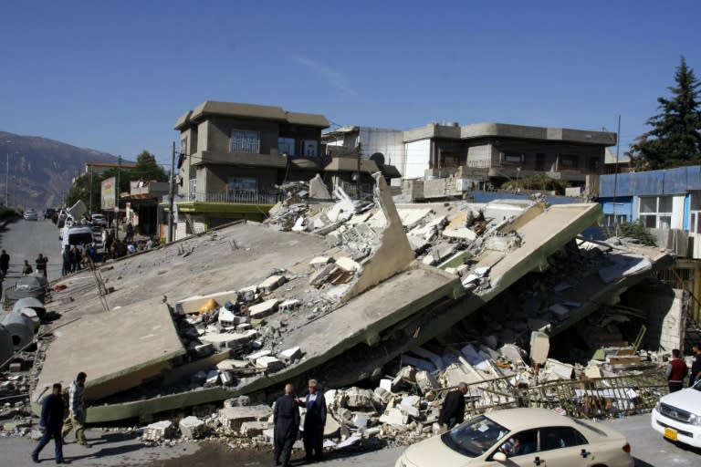 People gather around a levelled building in the mountainous town of Darbandikhan in Iraqi Kurdistan on November 13, 2017, following a 7.3-magnitude earthquake that hit the Iraq-Iran border area