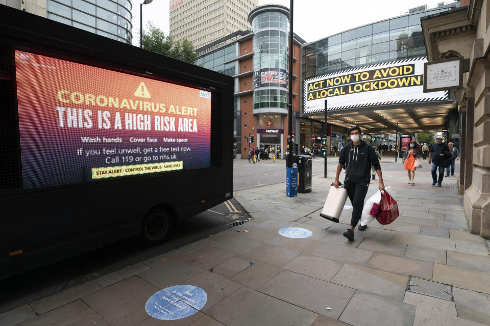 Members of the public are seen by public information messages in central Manchester after Prime Minister Boris Johnson set out new restrictions to last "perhaps six months" to slow the renewed spread of coronavirus, Manchester, England, Tuesday Sept 22, 2020. The UK has reached "a perilous turning point", Boris Johnson said as he set out a raft of new coronavirus restrictions for England. ( AP Photo/Jon Super)