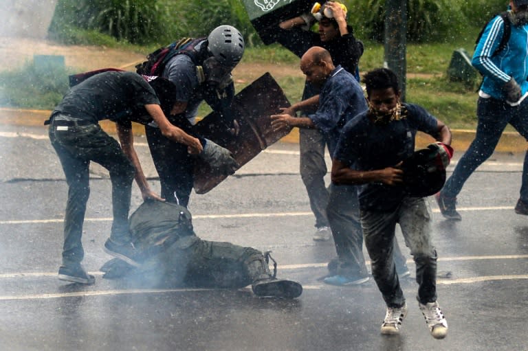 Opposition demonstrators kick a riot policeman during clashes in Caracas