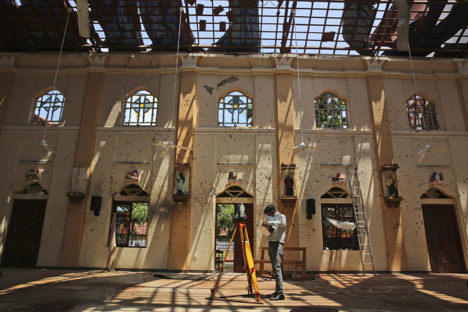 FILE- Sunlight steams in from gaping holes, as a surveyor works at St. Sebastian's Church, where a suicide bomber blew himself up on Easter Sunday in Negombo, north of Colombo, Sri Lanka, Thursday, April 25, 2019. The Easter suicide bombings at churches and hotels killed more than 260 people. (AP Photo/Manish Swarup)