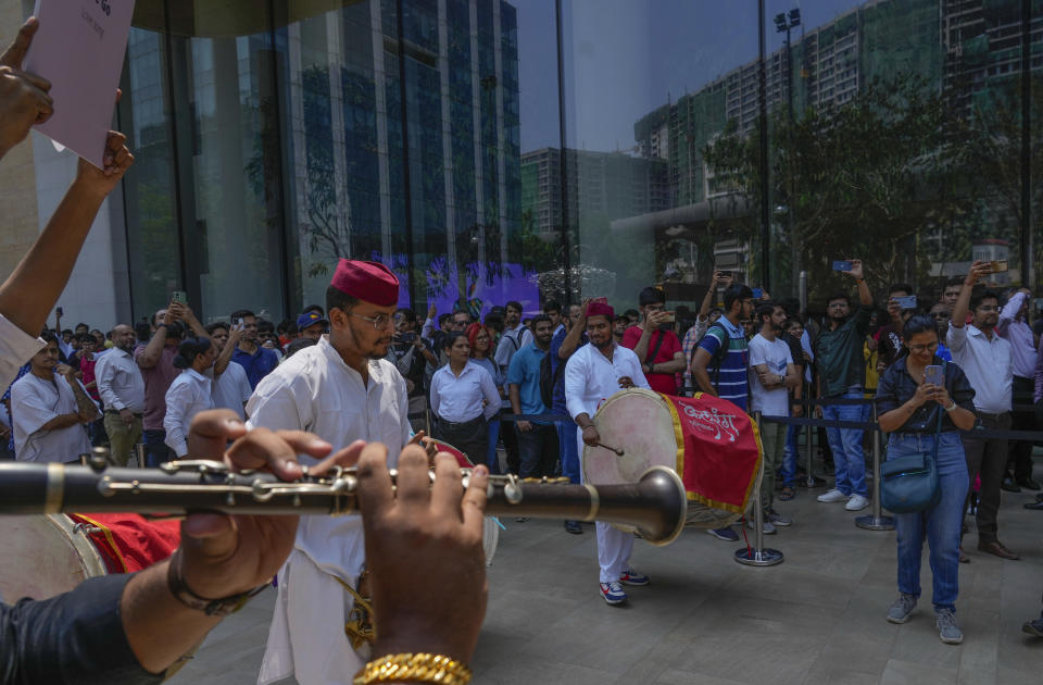 Artists play music as people wait in a queue during the opening of the first Apple Inc. flagship store in Mumbai, India, Tuesday, April 18, 2023. Apple Inc. opened its first flagship store in India in a much-anticipated launch Tuesday that highlights the company’s growing aspirations to expand in the country it also hopes to turn into a potential manufacturing hub. (AP Photo/Rafiq Maqbool)