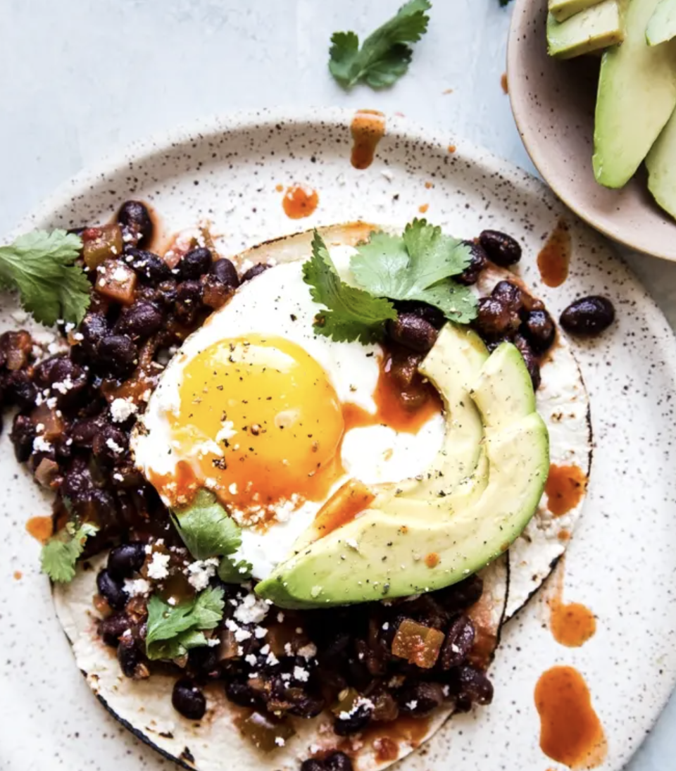 breakfast in bed huevos rancheros with black beans a fried egg avocado and hot sauce