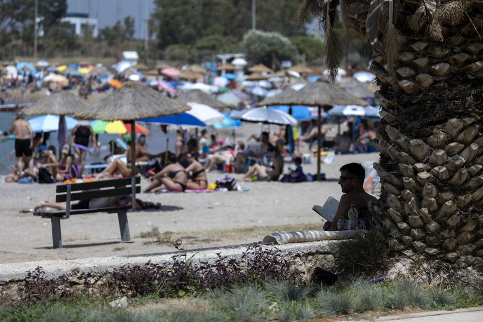 A man reads his book in the shadows of a tree at a beach, at Glyfada suburb, in Athens, Greece, Saturday, July 15, 2023. Temperatures reached up to 42 degrees Celsius in some parts of the country, amid a heat wave that continues to grip southern Europe. (AP Photo/Yorgos Karahalis)