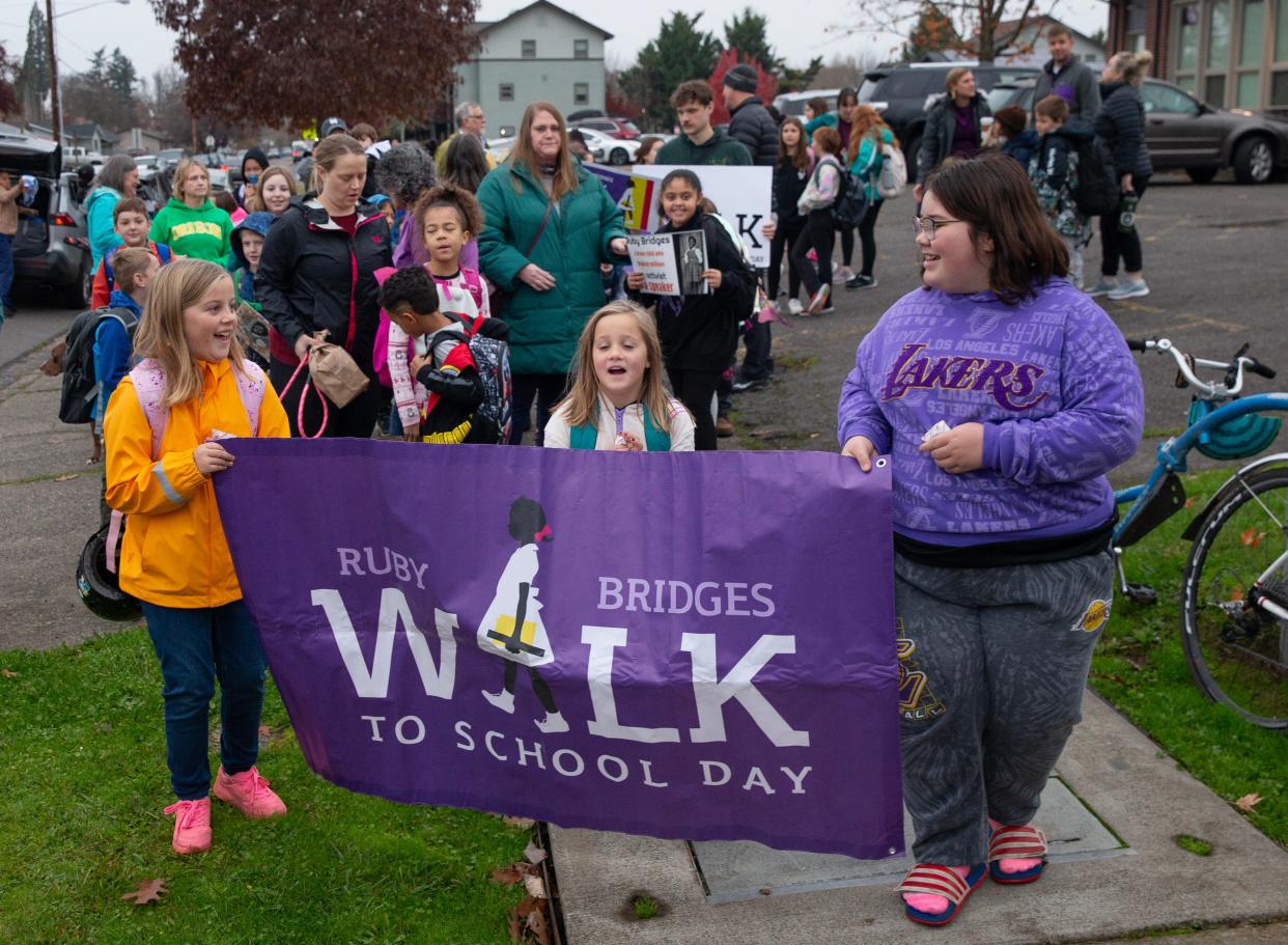 McCornack Elementary School students Jayce Morin, left, and Sophia Martinez, right, lead fellow students as they walk to their school during Ruby Bridges Walk to School Day in Eugene.