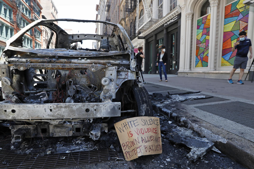 A message is perched against the carcass of a burned out police vehicle, Sunday, May 31, 2020, along a stretch of Broadway in Lower Manhattan in New York. Protesters angry over the death of George Floyd vandalized the area Saturday night. Floyd died in polcie custody in Minneapolis on Memorial Day. (AP Photo/Kathy Willens)