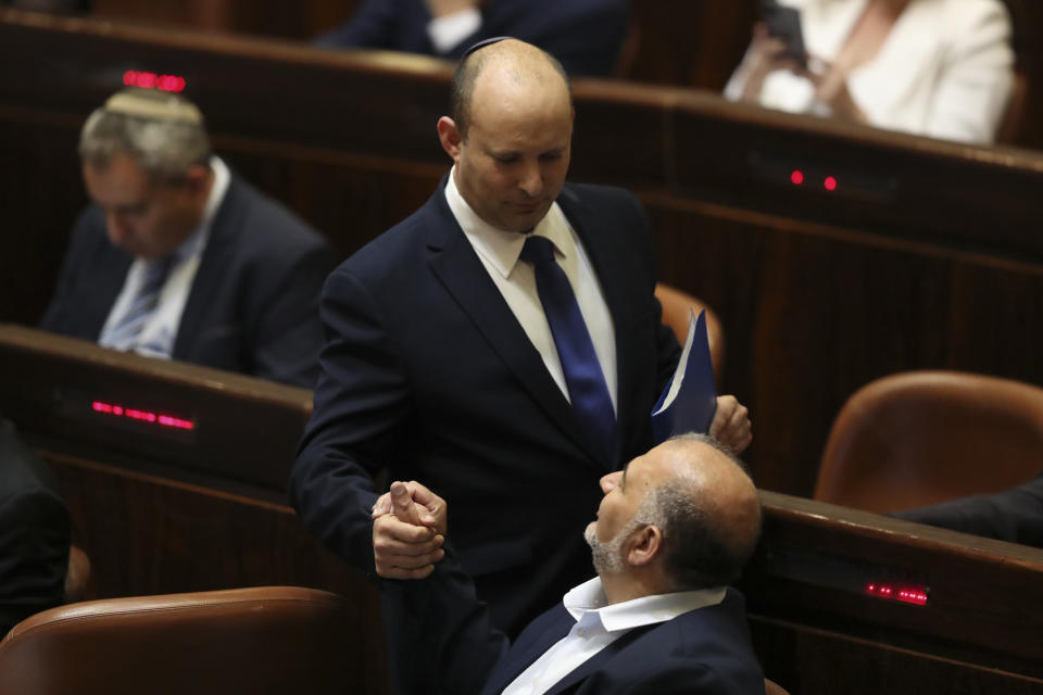 FILE - Israeli Prime Minister Naftali Bennett shakes hands with the leader of the United Arab List Mansour Abbas during a Knesset session in Jerusalem, June 13, 2021. Abbas broke a longstanding taboo when he joined Israel’s governing coalition last year. The bold move appears to be paying dividends: Abbas is the linchpin of the shaky union, securing hefty budgets and favorable policies for his constituents. (AP Photo/Ariel Schalit, File)