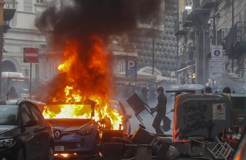 FILE - Supporters of the Eintracht Frankfurt soccer team set a police car afire as they clash with police in Naples, southern Italy, March 15, 2023, where their team is about to play a Champions League, round of 16, second leg soccer match against Naples. A recent surge in violence around soccer games is contributing to alarm over security when Germany hosts the European Championship. Some 22,000 police officers will be on duty each day for the tournament. (AP Photo/Salvatore Laporta, File)