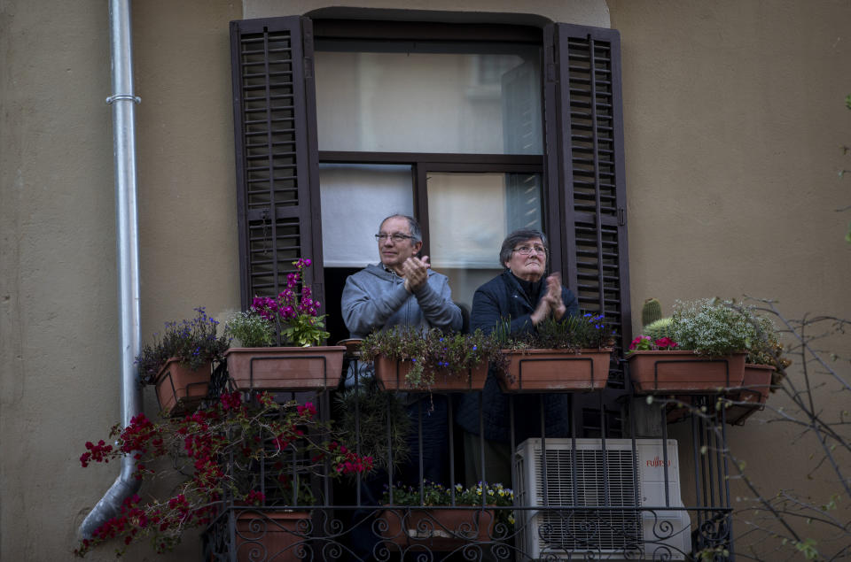 A couple applaud from their balcony in support of the medical staff that are working on the COVID-19 virus outbreak in Barcelona, Spain, Saturday, April 4, 2020. The new coronavirus causes mild or moderate symptoms for most people, but for some, especially older adults and people with existing health problems, it can cause more severe illness or death. (AP Photo/Emilio Morenatti)