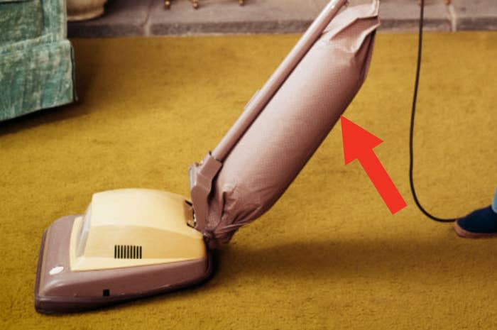 Closeup of a vacuum from the 1970s vacuuming harvest gold colored carpet
