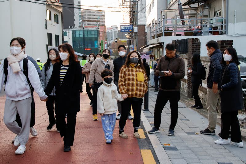 Students and their family members walk in front of an exam hall ahead of the annual college entrance examinations in Seoul