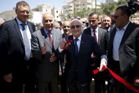 FIFA chief Sepp Blatter (C) gestures as he cuts the ribbon to open a playground during his visit to Dura al-Qar' village in the West Bank city of Ramallah May 20, 2015. REUTERS/Mohamad Torokman