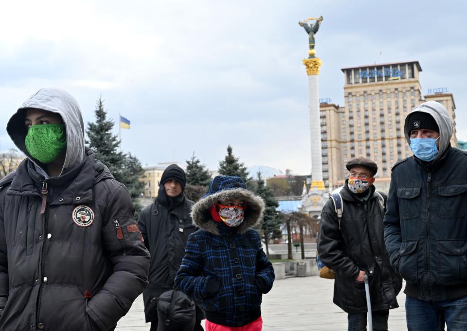 Homeless and vulnerable people wearing face masks, amid concerns over the spread of the novel coronavirus COVID-19, keep their distance from each other while queuing to get free meals distributed by charity activists at the Independence Square in the capital of Kiev on April 1, 2020. (Photo by Sergei SUPINSKY / AFP) (Photo by SERGEI SUPINSKY/AFP via Getty Images)